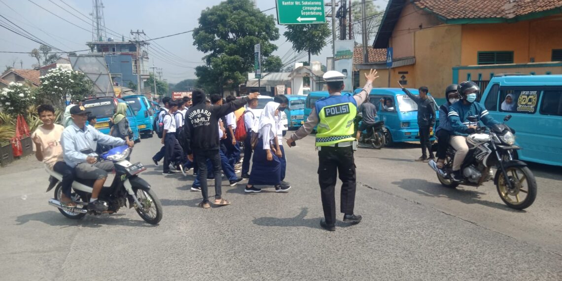 Wujud Kepedulian,Unit Lantas Polsek Sukalarang  Bantu Anak Sekolah Menyeberang Jalan