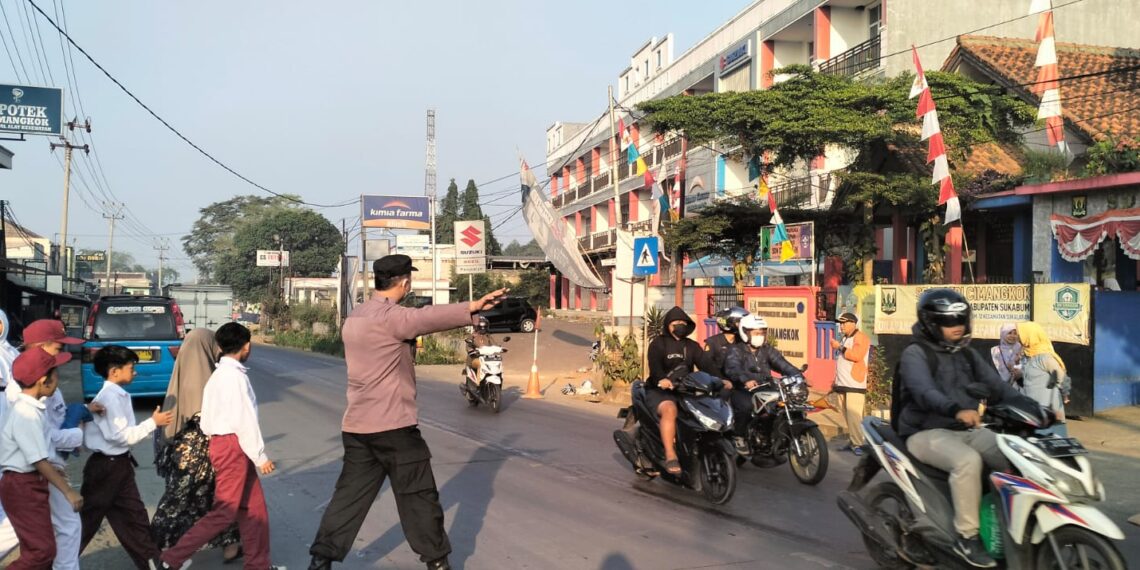 Wujud Kepedulian Polri, Personel Unit Samapta Polsek Sukalarang Bantu Anak Sekolah Menyebrang Jalan