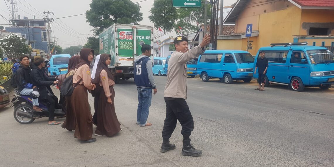 Polisi Polsek Sukalarang Bantu Anak-Anak Sekolah Menyeberang Jalan Sepulang Sekolah