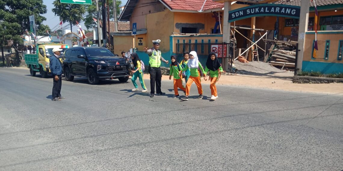 Wujud Kepedulian, Polisi Polsek Sukalarang Bantu Anak-Anak Sekolah Menyeberang Jalan Sepulang Sekolah