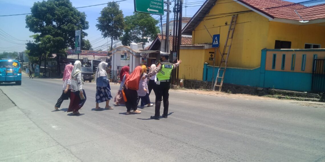 Wujud Kepedulian, Polisi Unit Lantas Polsek Sukalarang Bantu Masyarakat Menyeberang Jalan