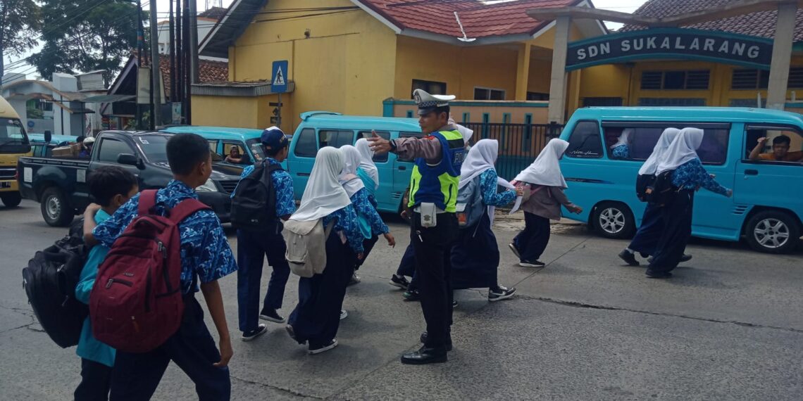 Wujud Kepedulian, Polisi Polsek Sukalarang Bantu Anak-Anak Sekolah Menyeberang Jalan Sepulang Sekolah