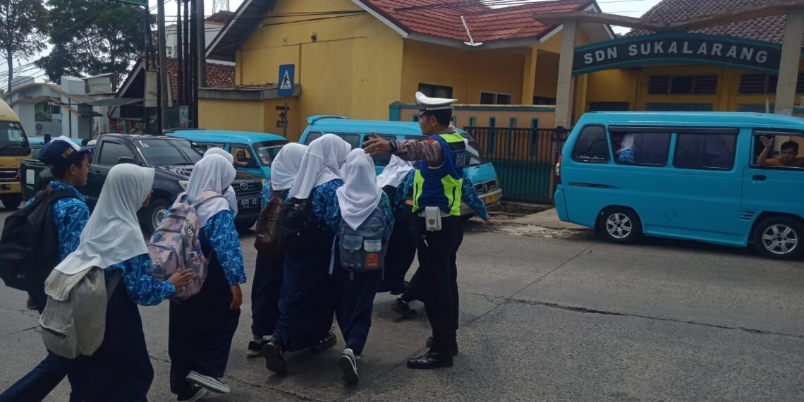 Wujud Kepedulian, Polisi Polsek Sukalarang Bantu Anak-Anak Sekolah Menyeberang Jalan Sepulang Sekolah