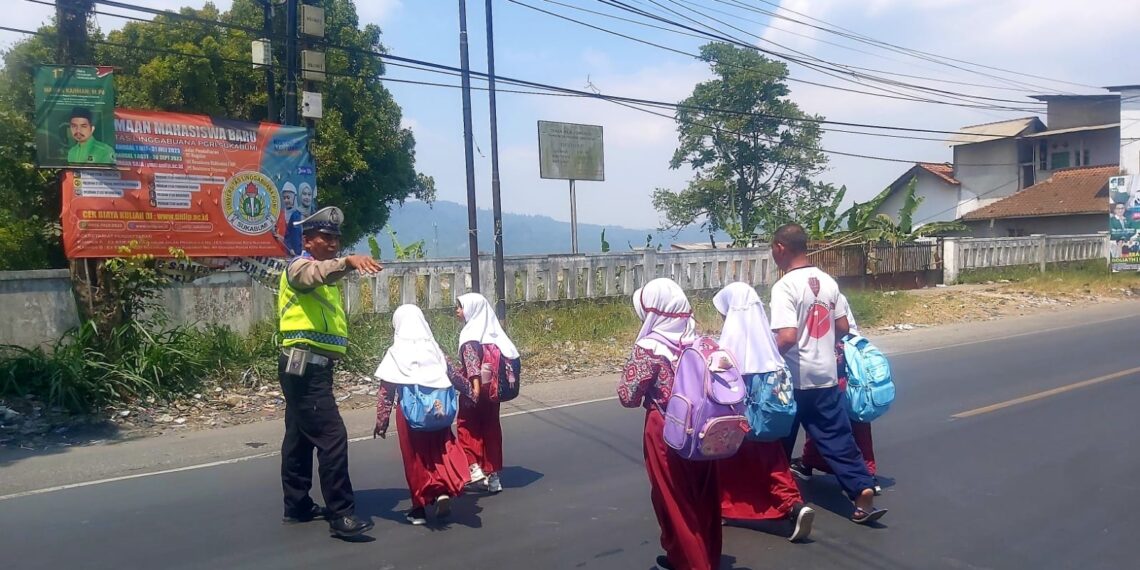 Unit Lalu Lintas Polsek Sukalarang Bantu Anak Menyeberang Jalan
