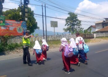 Unit Lalu Lintas Polsek Sukalarang Bantu Anak Menyeberang Jalan