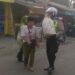 Anggota Unit Polsek Sukaraja Menolong mengangkat barang jualan kakek Yang Tampak Kesulitan Membawa Sebuah Karung