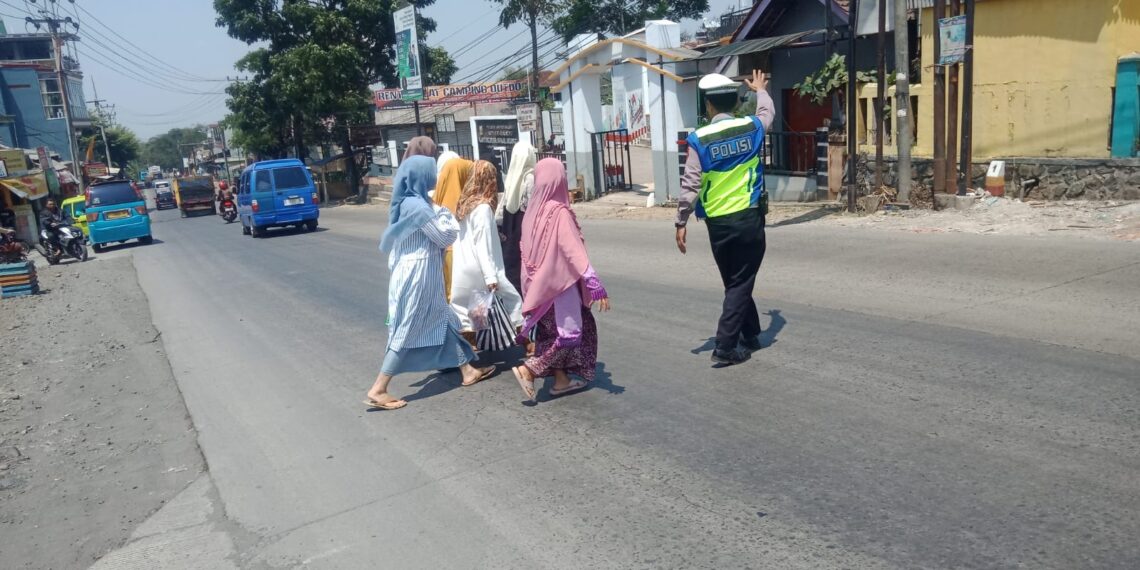 Wujud Kepedulian, Polisi Unit Lantas Polsek Sukalarang Bantu Masyarakat Menyeberang Jalan