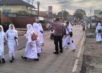Wujud Kepedulian, Personil Polsek Sukalarang  Bantu Anak Sekolah Menyeberang Jalan
