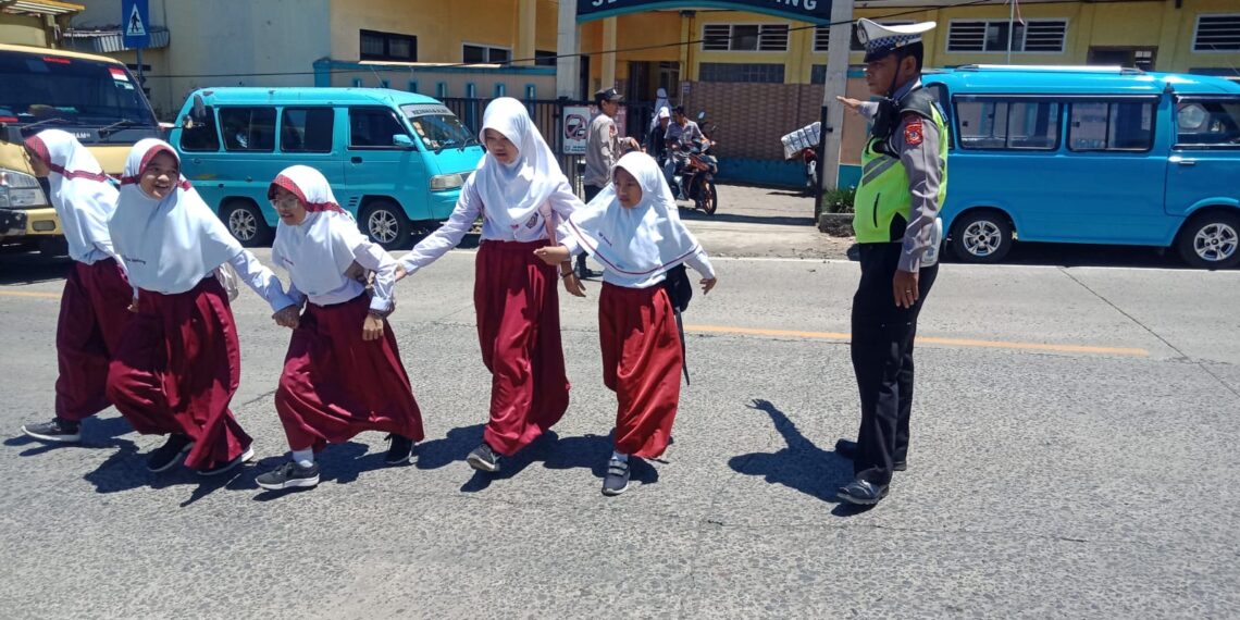 Wujud Kepedulian,Polisi Polsek Sukalarang  Bantu Anak Sekolah Menyeberang Jalan