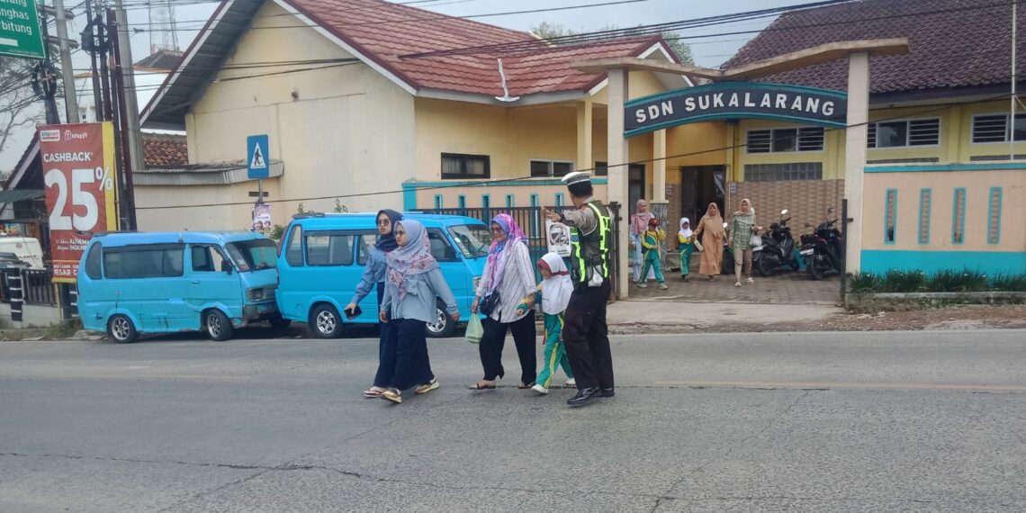 Wujud Kepedulian,Unit Lantas Polsek Sukalarang Bantu Anak Sekolah Menyeberang Jalan